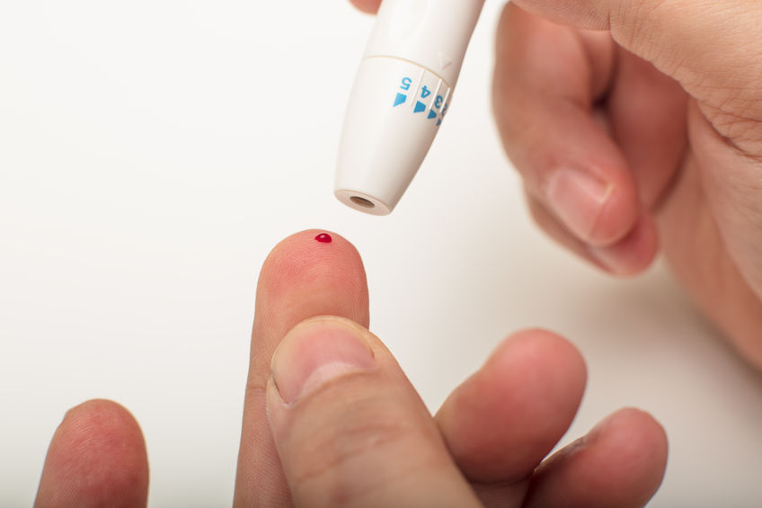 Diabetic using a lancet to take a blood sample by pricking the tip of his finger in a close up view showing the first drop of blood low testosterone blood test